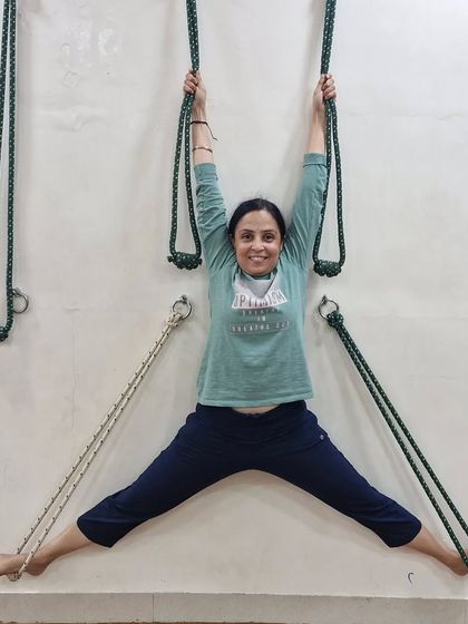 A student enjoying a full body stretch on the rope wall. This is an excellent way to open up the hips and shoulders, using the ropes for support and balance.