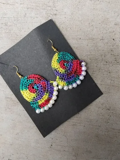 A detailed look at the multicolored pearl-edged earrings. The rainbow yarn makes each pair unique.