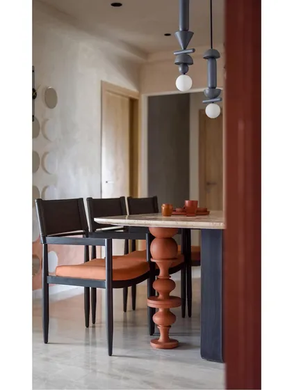 A different angle of the dining area, showing the beautiful contrast between the warm wood of the chairs and the cool stone of the table.