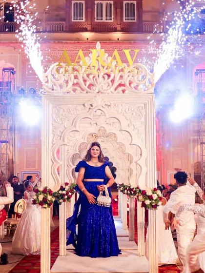 The bride's anniversary entrance is made even more spectacular with cold-fire pyrotechnics erupting as she enters. The backdrop of the illuminated Chomu Palace adds to the royal feel.