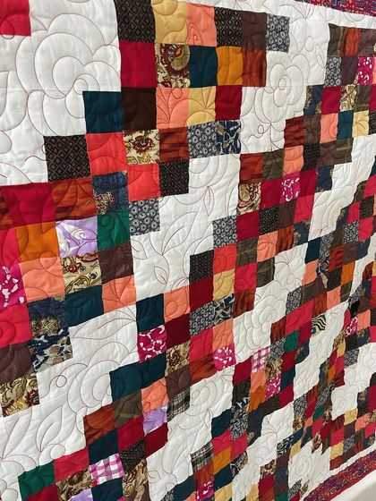 An angled view of the scrappy quilt, showing the floral quilting pattern.