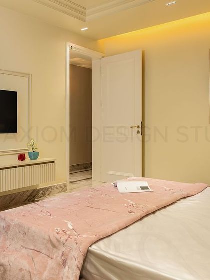 The TV unit in the color-blocked bedroom features a fluted console and is framed by simple wall molding, maintaining a clean and harmonious aesthetic.