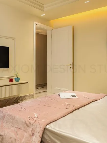 The TV unit in the color-blocked bedroom features a fluted console and is framed by simple wall molding, maintaining a clean and harmonious aesthetic.