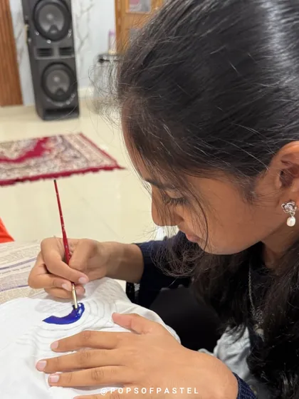 A young artist carefully paints a blue moon on her bucket hat during a rainbow-themed party.