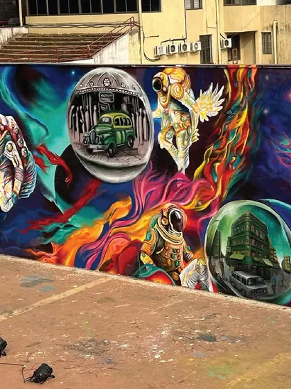 The other side of the mural, showing astronauts exploring a colorful cosmos filled with bubbles of earthly scenes, like a classic Mumbai taxi. It’s a surreal blend of the future and the present.