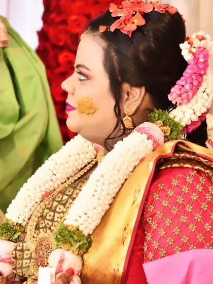 A side profile showing the details of a Sreemantham hairstyle. You can see the carefully placed flowers in her hair and the flawless makeup application, designed to look perfect from every angle.