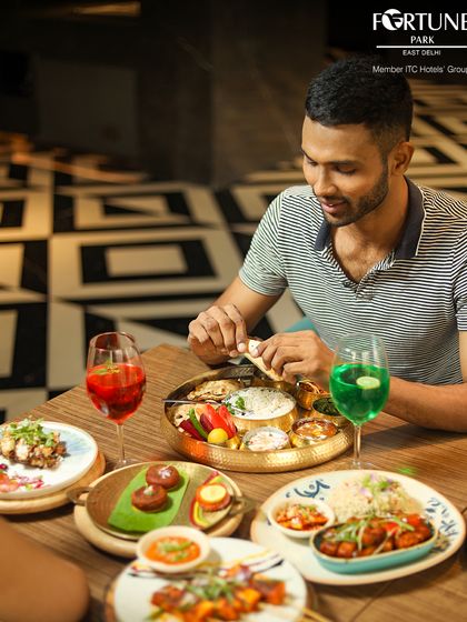 A guest enjoying a traditional Indian thali at Zodiac, surrounded by a colorful spread of dishes and vibrant drinks.
