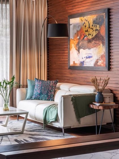 In a world full of trends, I love creating timeless spaces that age well. This corner of a living room features a comfortable leather sofa set against a warm, reeded wood wall, accented with a piece of vibrant abstract art.