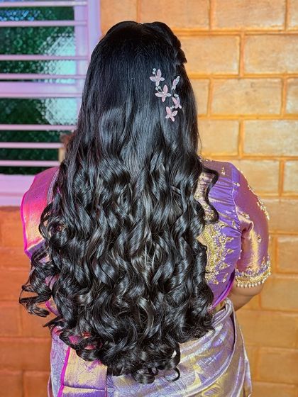 A modern reception hairstyle with beautiful, bouncy curls and a stylish butterfly accessory. This look is perfect for a bride who wants something fun and glamorous.