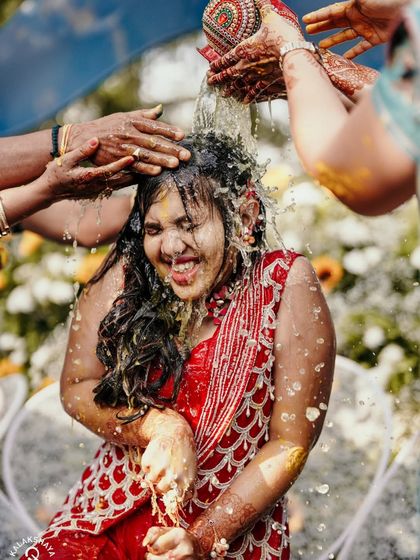 A dynamic shot of the bride getting drenched with water during a fun Haldi ritual.