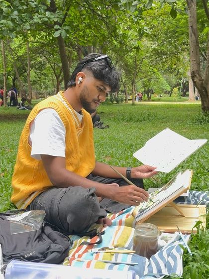 Another angle of me painting at the park, showing my setup with my easel and supplies spread out on a blanket.