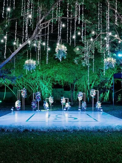 I transformed this outdoor space into an enchanted forest for a cocktail party. A custom dance floor sits under a canopy of trees, with cascading fairy lights and hanging floral arrangements that create a magical, starlit atmosphere for an evening of celebration.