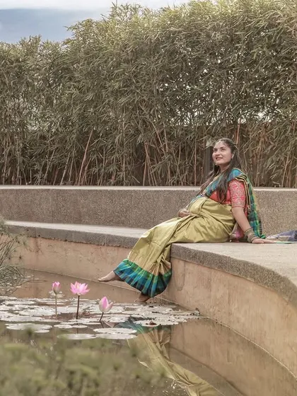 A peaceful moment by a lily pond, with the mom-to-be dipping her toes in the water, dressed in a lovely traditional saree.