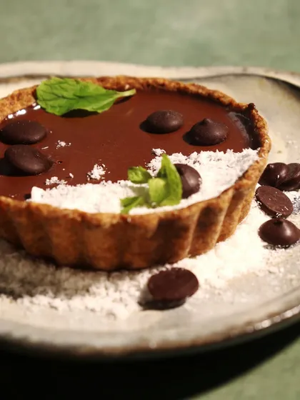 A close-up of our Dark Chocolate Coconut Tart. This treat is completely sugar-free, high in plant-based protein, and 100% vegan. You get a rich, decadent flavor experience that perfectly aligns with your fitness goals.