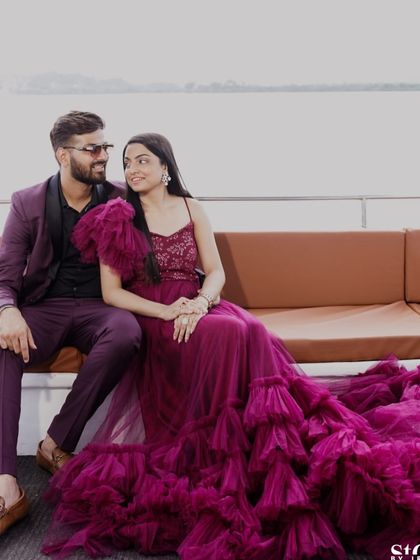 A seated shot of the couple on the boat, showing the texture and color of the magenta gown up close.