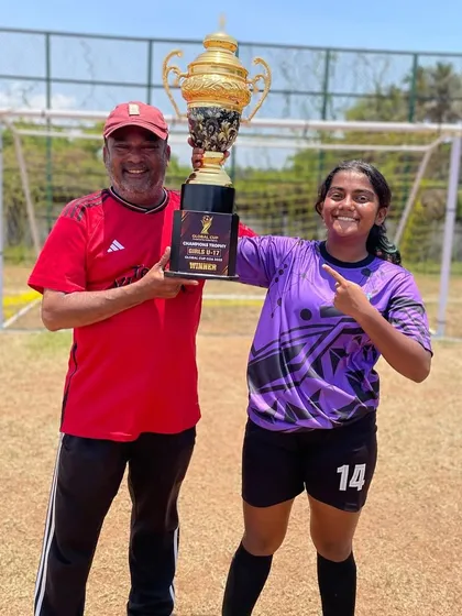 Our coach and a player posing with the Global Cup trophy, a symbol of our successful youth development program.
