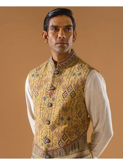 A close-up of a mustard-yellow Jawahar jacket with intricate, multi-colored geometric and traditional embroidery. This piece from our RAAYA collection is a perfect example of bespoke brilliance.