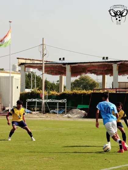 A player skillfully maneuvers the ball past two defenders during a practice match against Zinc FC, with the Indian flag in the background.