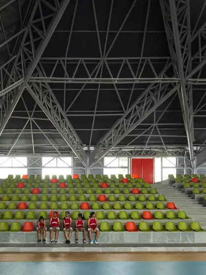 The tiered seating provides clear sightlines to the court, ensuring an excellent viewing experience for spectators. The red doors at the top provide access and a point of visual focus.