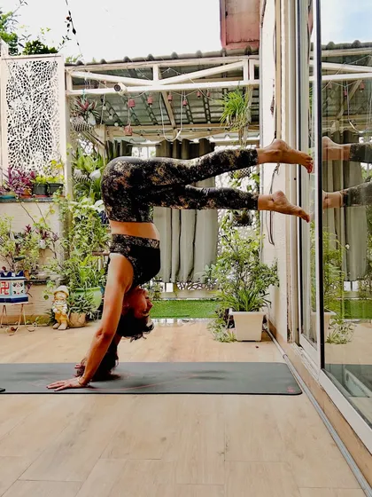 A wall-assisted handstand variation, building core strength and confidence with inversions. This pose embodies the philosophy of 'effortless action,' letting the breath lead and the body follow.