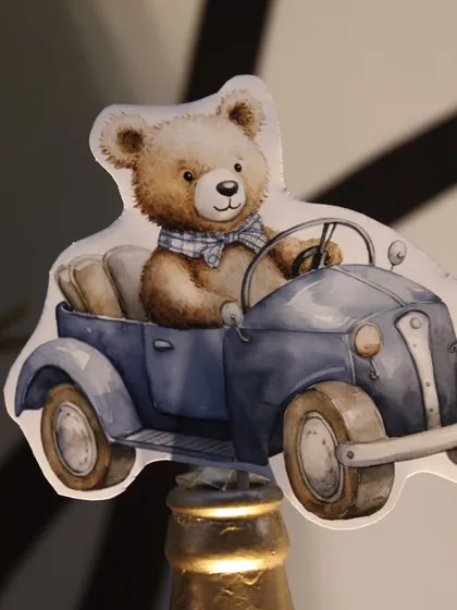 A beautifully illustrated cutout of a teddy bear driving a vintage convertible. This was used as a topper for a decorative bottle, adding a whimsical touch to the decor.