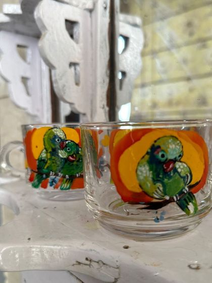 A pair of our quirky parrot-themed tea glasses, adding a pop of color to your kitchen shelf.