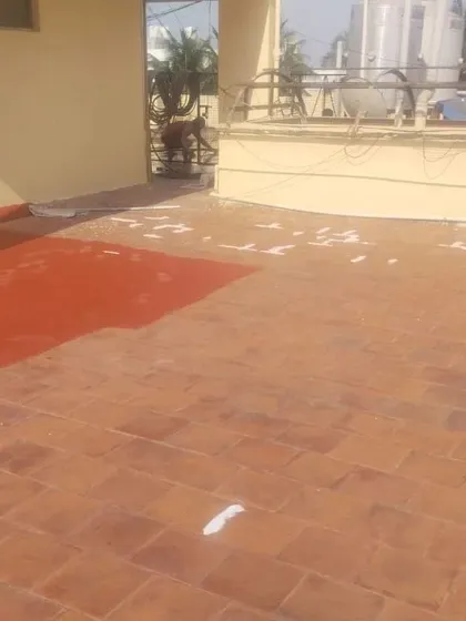 This image captures the waterproofing application in progress. You can see the original terracotta tiles being covered by the new protective red coating, demonstrating the transformation and coverage achieved.