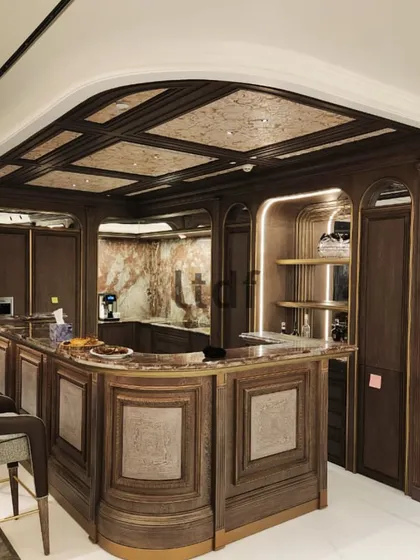 This grand bar setting transcends the conventional with an emphasis on minute details and organic forms, all within a traditional vintage framework. Wooden furnishings with metallic hints evoke rustic elegance, while marble accents enrich the space, creating a nostalgic atmosphere.