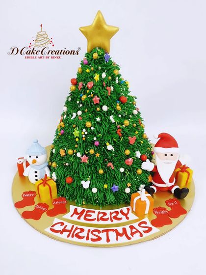 A fun Christmas tree-shaped cake, fully decorated with colorful sprinkles and surrounded by Santa, a snowman, and presents.
