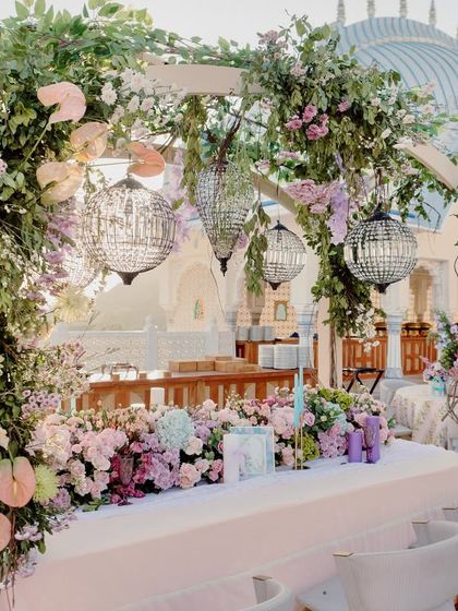 A stunning head table for the couple, set under a floral arch with hanging crystal ball lanterns, overlooking the Jaipur skyline.