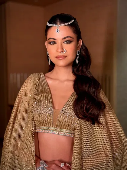 The complete look, with the golden outfit and modern matha patti. The makeup ties everything together, creating a look that is both traditional in essence and contemporary in execution.