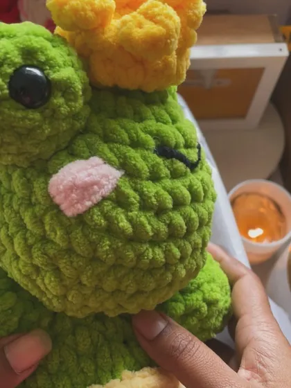 A close-up of the frog prince, showing off his sleepy eyes and cute pink cheeks. This plushie is packed with personality.