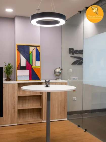 A corner in the office where creativity meets functionality. The combination of modern art, a sleek high-top table, and a halo light fixture creates a dynamic and inspiring breakout space.