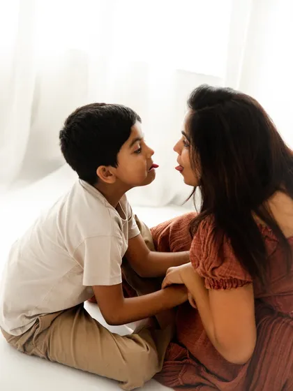 A playful moment of connection. Sticking their tongues out at each other, this mother and son show their fun-loving bond in a silly and sweet way.