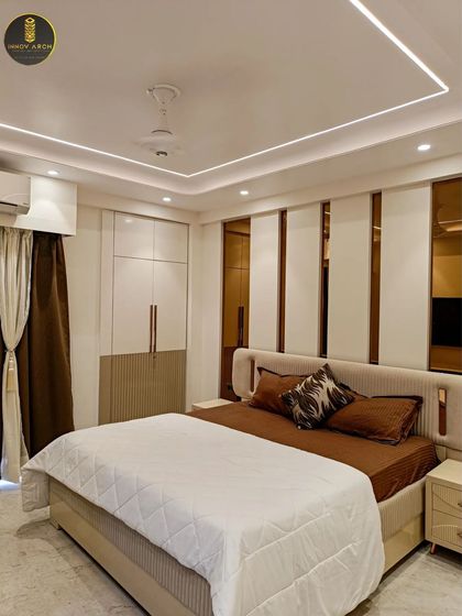 The master bedroom at Uninav Bliss, featuring a custom headboard wall with alternating panels of white and bronze mirror. The integrated wardrobe and soft ceiling lights complete this modern and sophisticated look.