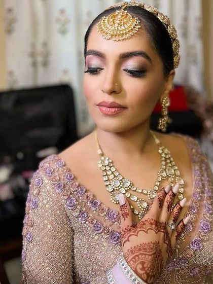 A close-up of a bride's beautiful makeup and jewelry, with her mehendi-adorned hand adding to the elegance.