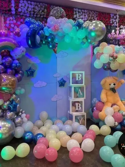 A whimsical "Oh Baby" setup with a rainbow, clouds, and a teddy bear. The pastel balloons and "BABY" blocks make this a perfect backdrop for a baby shower.