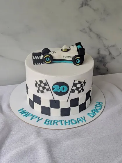 Turning 20 on full throttle! This Formula 1 themed cake features a checkered flag pattern and a handcrafted Mercedes F1 car on top.