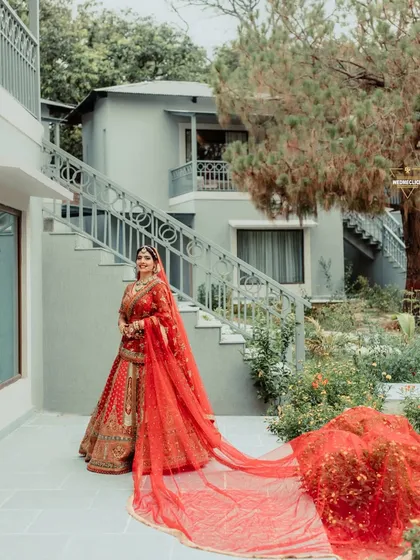 The bride poses with her dramatic long red veil, creating a striking and fashionable bridal portrait.