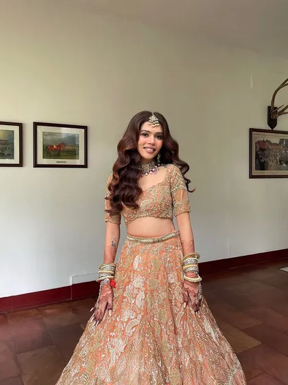 The bride's full look. The open hairstyle with a maang tikka is a stunning choice for a modern bride.