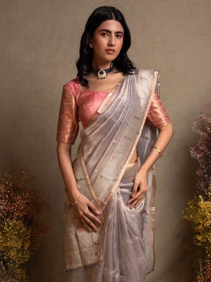 A silver organza saree with a traditional Paithani border and munia motifs, blending lightness with rich heritage.
