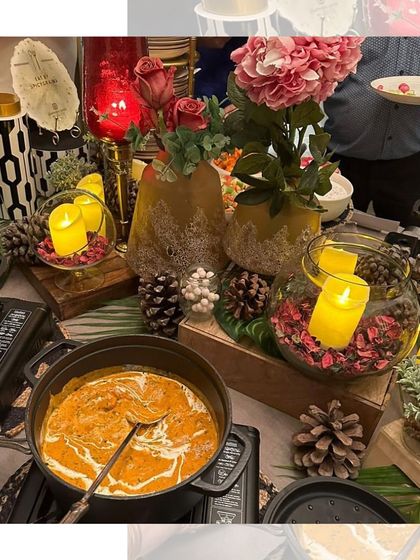 A close-up of our hot buffet section, with rich curries simmering in pots. The table is decorated with candles and flowers, adding to the warm and inviting feel.