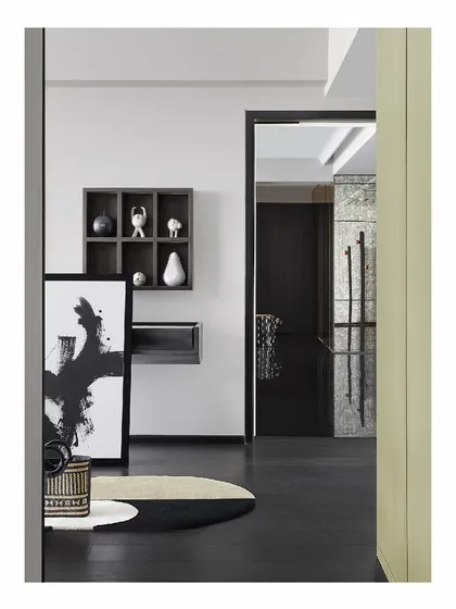 The entry to the 'Reflections' home sets a monochromatic and artistic tone. An abstract painting is propped against the wall, and curated objects sit in a shadow box, creating an interesting composition that welcomes you into the space.