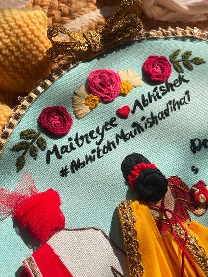 A detailed shot of the hand embroidered names and flowers on a wedding hoop. Every stitch is done with care to make sure it's perfect for the couple.
