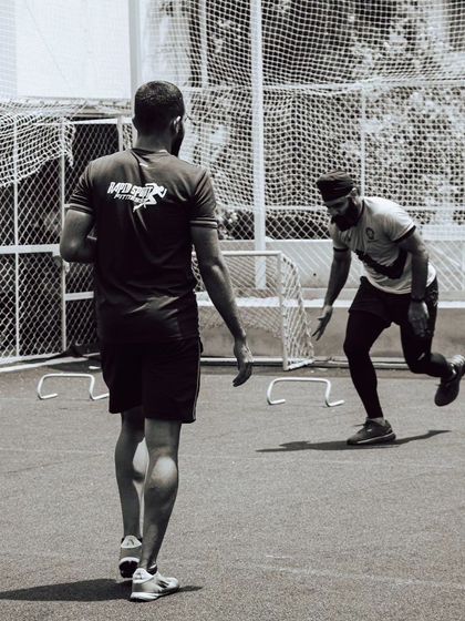 An athlete works on plyometric hurdle drills under the watchful eye of a coach. This type of training is essential for developing explosive power and coordination.