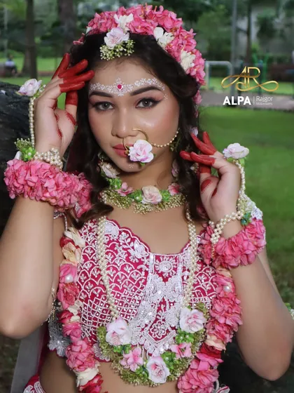 The complete Radha look, featuring a white and pink lehenga, extensive floral jewelry, and delicate white चंदन (chandan) art on the forehead.