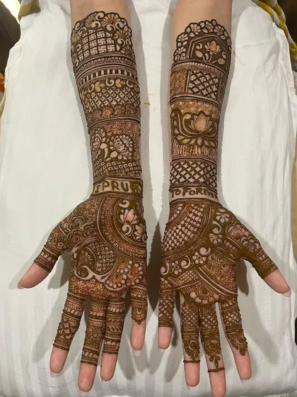 A complete bridal mehndi set with the couple's names, "PRU" and "FOR," subtly integrated into the design on the forearms. This is a wonderful way to personalize your wedding henna.