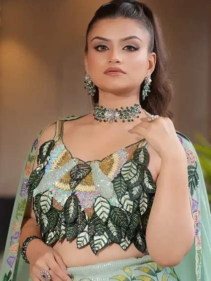 This shot highlights the unique, wing-like design of the blouse on the pastel green lehenga, crafted with sequins and threadwork.