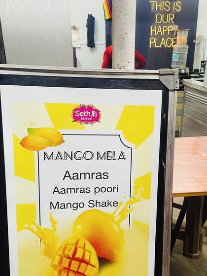 A sign for our "Mango Mela" event. During mango season, we offer special treats like Aamras Poori and Mango Shake.