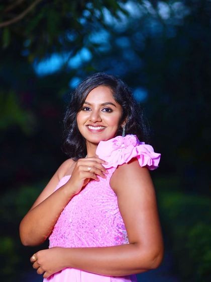 A happy, close-up portrait of a woman in a pink gown, with the soft, out-of-focus garden background adding to the charm.